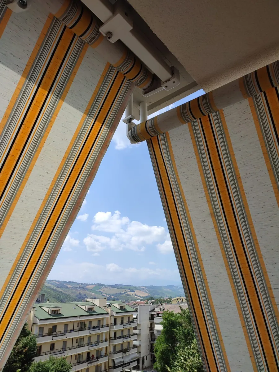 Tenda da sole a strisce colorate su terrazzo con vista sulle colline abruzzesi - IS Metal srl Teramo